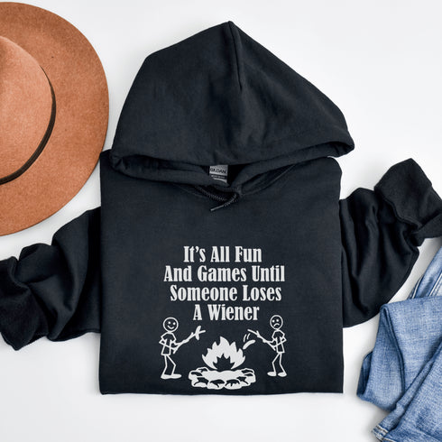 Our Camping hoodie features two adorable stick figure people roasting wieners over a cozy campfire. And with the hilarious slogan "It's All Fun & Games Until Someone Loses A Wiener," you'll be the life of the party at any camping trip!